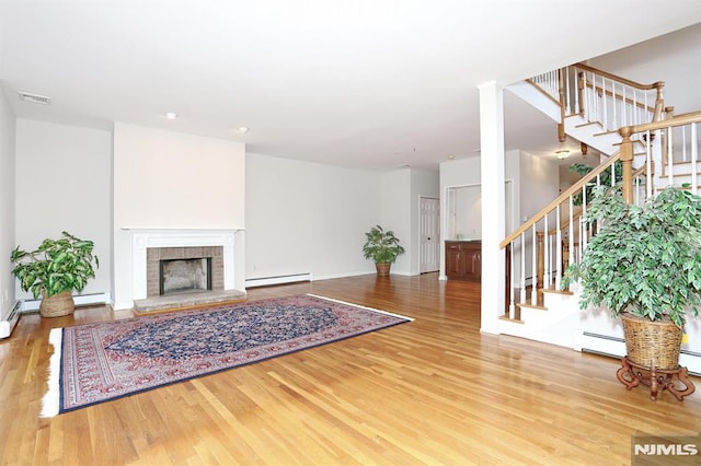 living room with a baseboard heating unit, a brick fireplace, and hardwood / wood-style flooring