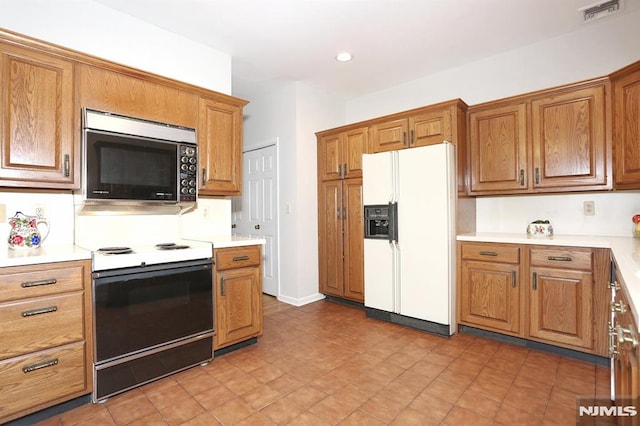 kitchen with range with electric cooktop and white refrigerator with ice dispenser