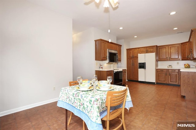 tiled dining room with ceiling fan and sink