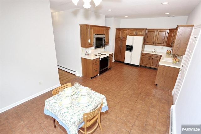 kitchen with baseboard heating, white appliances, and sink