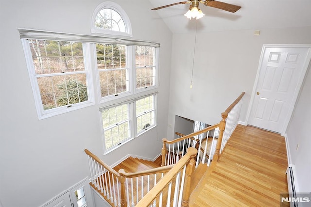 stairs with vaulted ceiling, ceiling fan, baseboard heating, and hardwood / wood-style flooring