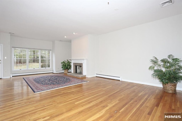 living room featuring a fireplace, light hardwood / wood-style floors, and a baseboard radiator