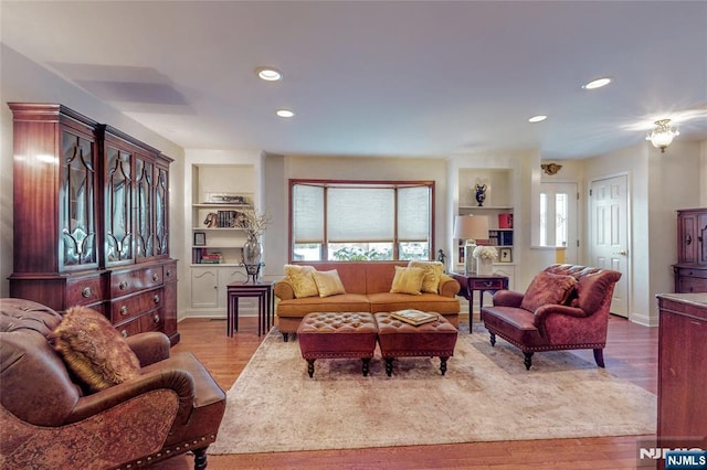 living room with built in features and light hardwood / wood-style floors