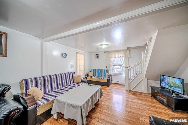 living room with a baseboard heating unit and light hardwood / wood-style flooring