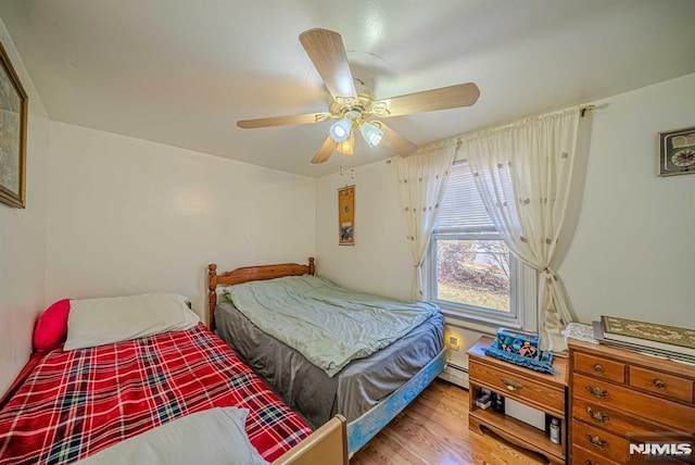 bedroom featuring a baseboard heating unit, light wood-type flooring, and ceiling fan