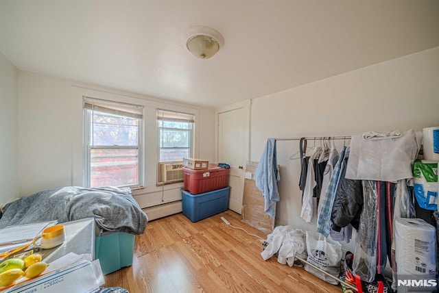 bedroom featuring a baseboard heating unit, light hardwood / wood-style floors, and cooling unit