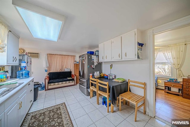 kitchen with white cabinets, stainless steel fridge, light tile patterned floors, and sink