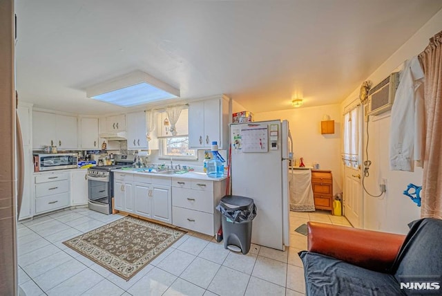 kitchen featuring light tile patterned floors, white refrigerator, sink, white cabinetry, and gas range