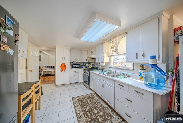 kitchen with sink, white cabinetry, light tile patterned floors, and appliances with stainless steel finishes