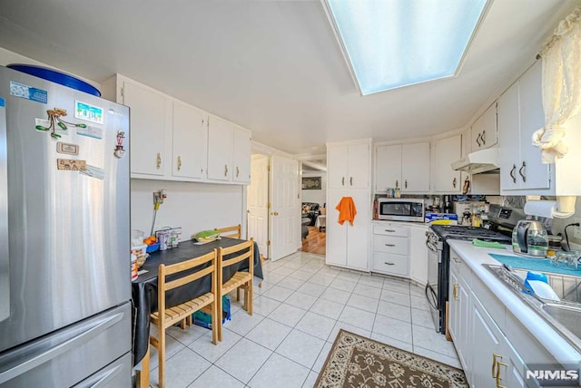 kitchen with stainless steel appliances, light tile patterned flooring, white cabinetry, and sink