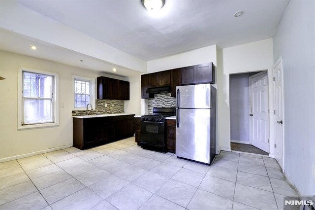 kitchen featuring decorative backsplash, stainless steel fridge, black gas range, and dark brown cabinetry