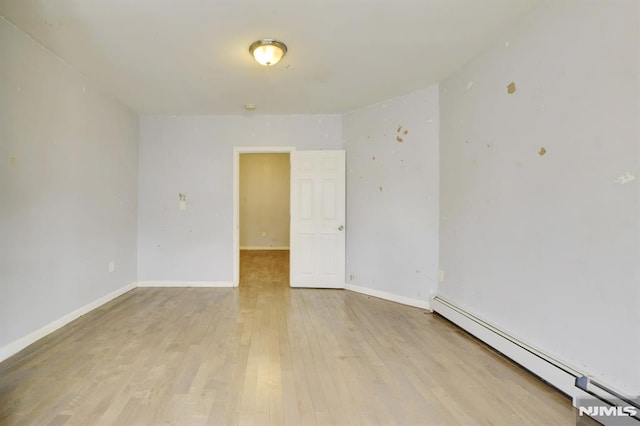 unfurnished room featuring light hardwood / wood-style floors and a baseboard heating unit