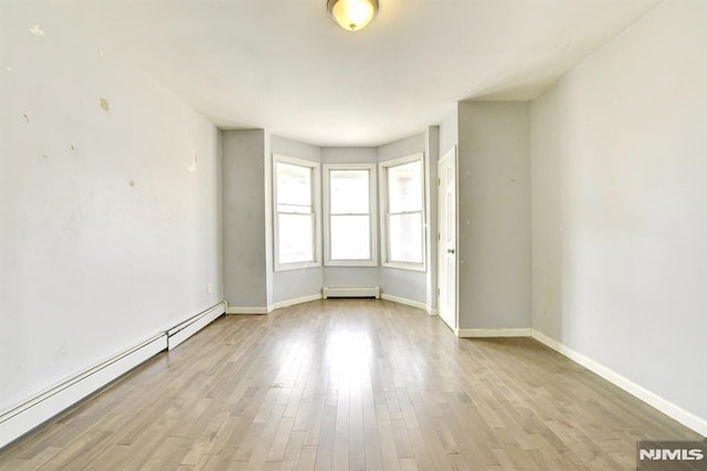 empty room with a baseboard radiator and light hardwood / wood-style floors