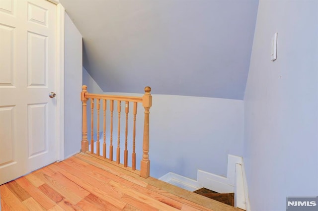 staircase featuring wood-type flooring and vaulted ceiling