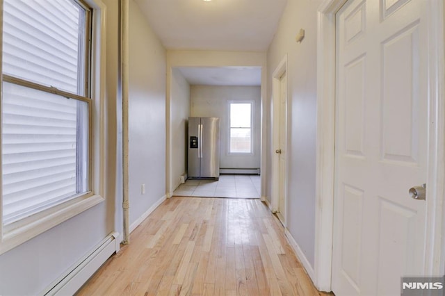 hall with light hardwood / wood-style flooring and a baseboard heating unit