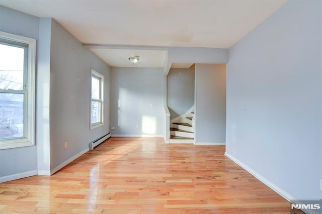 unfurnished room featuring a baseboard radiator and light hardwood / wood-style flooring