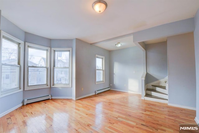 unfurnished room with baseboard heating, a wealth of natural light, and light hardwood / wood-style flooring