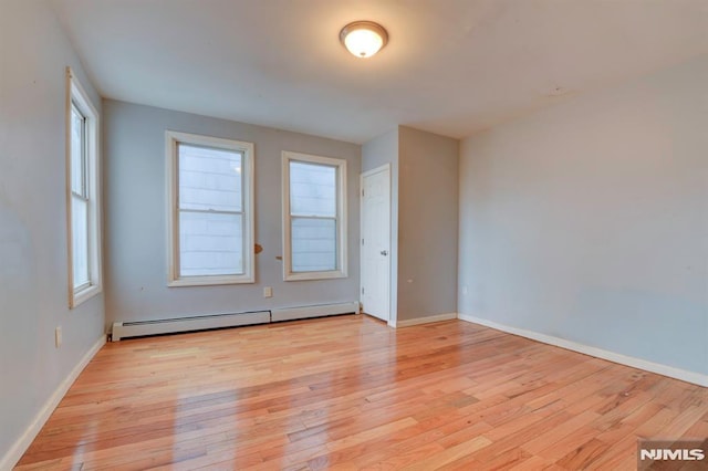 spare room featuring plenty of natural light, light hardwood / wood-style floors, and a baseboard heating unit