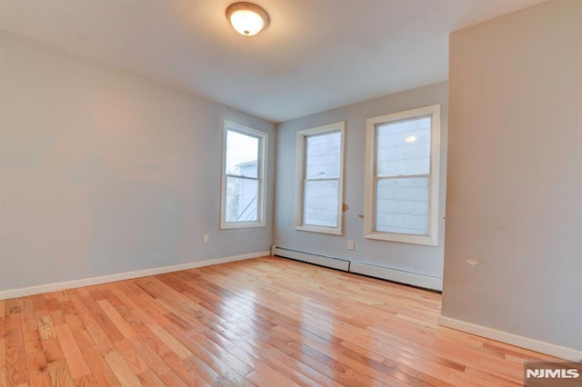 empty room featuring a baseboard radiator and light hardwood / wood-style flooring