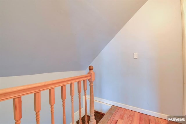 staircase with hardwood / wood-style floors and vaulted ceiling