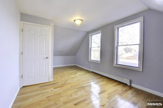 bonus room featuring light wood-type flooring, vaulted ceiling, and baseboard heating