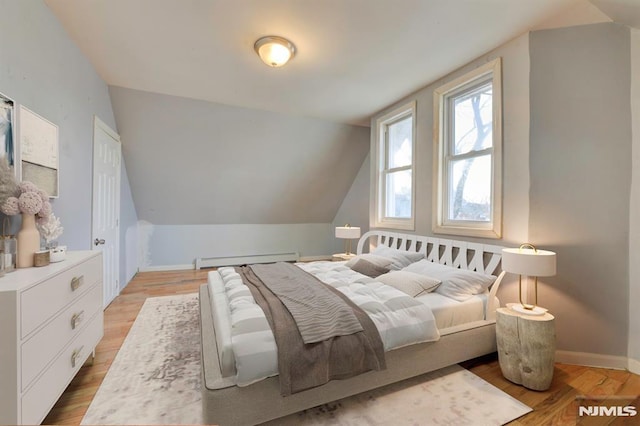 bedroom featuring a baseboard radiator, vaulted ceiling, and light wood-type flooring