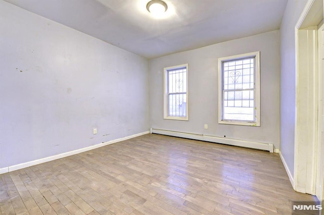 unfurnished room with light wood-type flooring and a baseboard heating unit