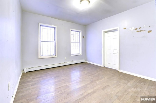 spare room featuring a baseboard radiator and light wood-type flooring