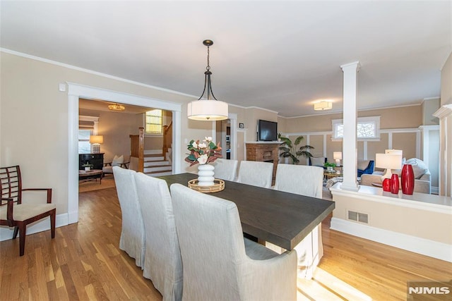 dining room with decorative columns, light hardwood / wood-style flooring, and ornamental molding