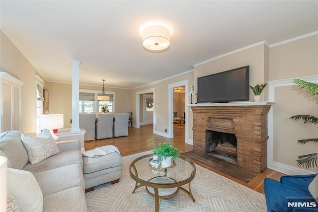 living room featuring wood-type flooring, ornamental molding, and ornate columns