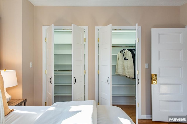 bedroom featuring dark hardwood / wood-style floors and multiple closets