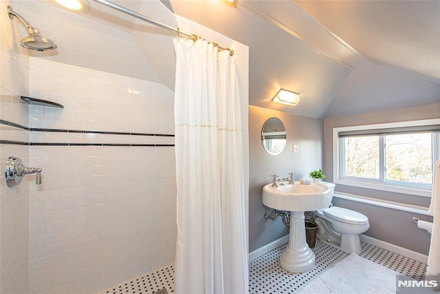 bathroom featuring a shower with shower curtain, toilet, and lofted ceiling