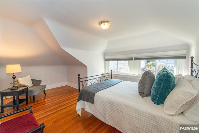 bedroom with wood-type flooring and vaulted ceiling