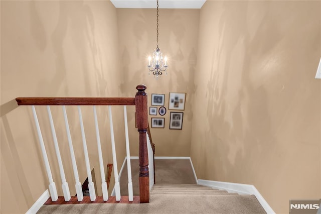 stairs with carpet floors and a notable chandelier