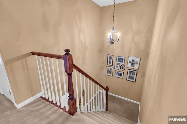 staircase with carpet floors and an inviting chandelier