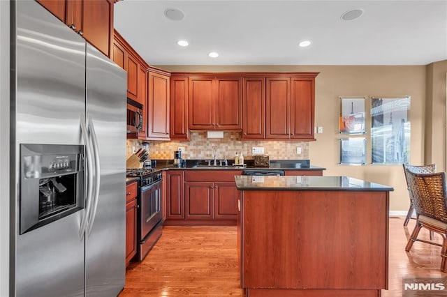 kitchen featuring light hardwood / wood-style floors, appliances with stainless steel finishes, decorative backsplash, sink, and a center island