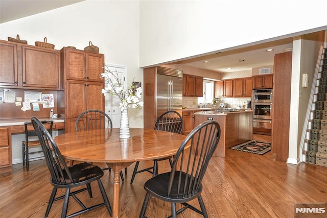 dining space featuring a towering ceiling and light hardwood / wood-style flooring