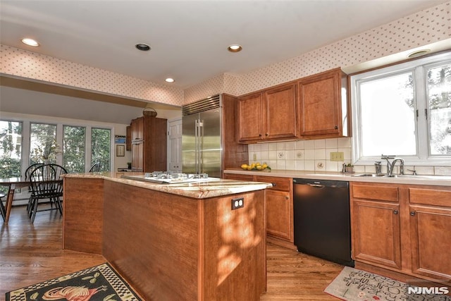 kitchen with light hardwood / wood-style flooring, a center island, built in fridge, black dishwasher, and sink