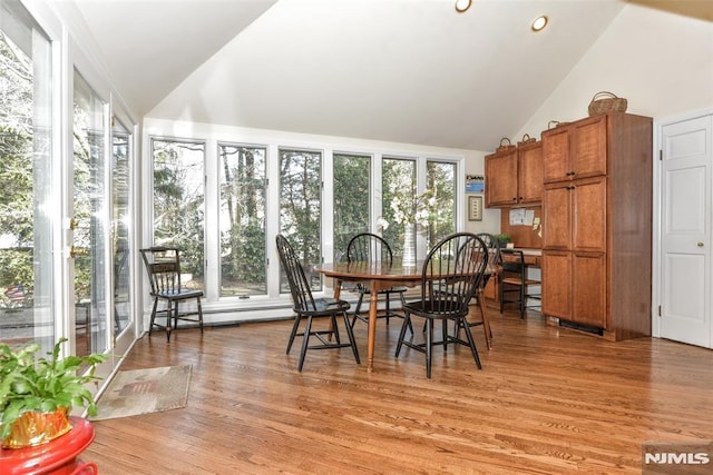 dining space featuring light wood-type flooring and vaulted ceiling