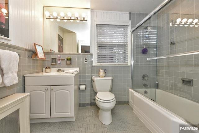 full bathroom with tile patterned flooring, toilet, enclosed tub / shower combo, vanity, and tile walls