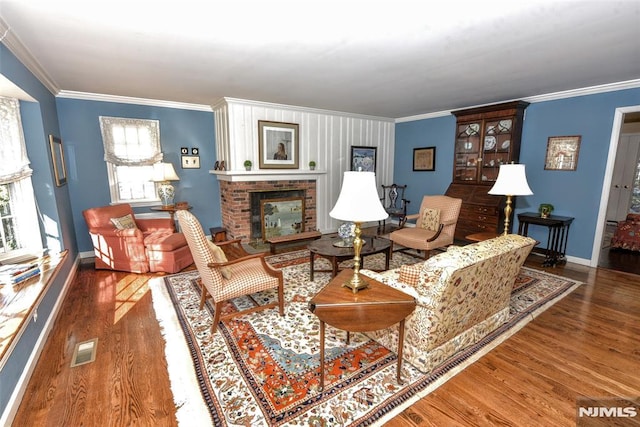 living room with a brick fireplace, ornamental molding, and dark hardwood / wood-style floors