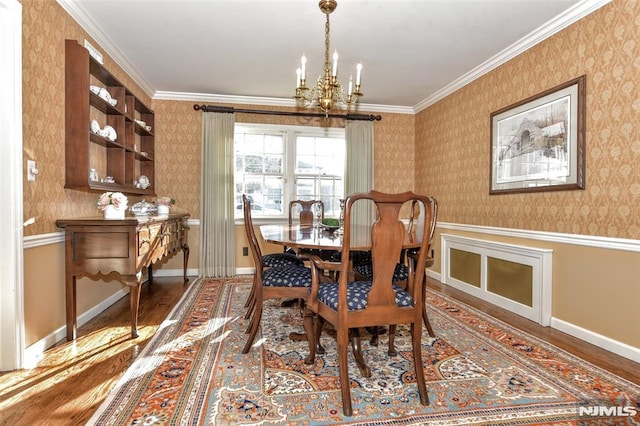 dining area with hardwood / wood-style floors, ornamental molding, and a notable chandelier