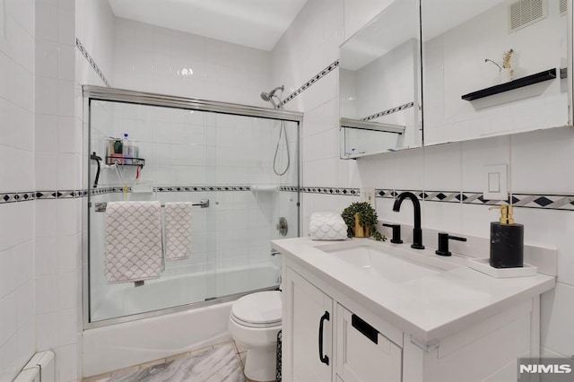 full bathroom with enclosed tub / shower combo, tile walls, toilet, vanity, and decorative backsplash