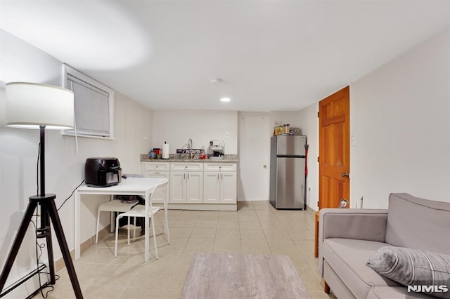 kitchen featuring white cabinets, stainless steel refrigerator, and baseboard heating