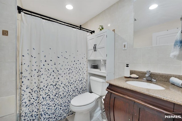 bathroom featuring curtained shower, tile walls, toilet, and vanity