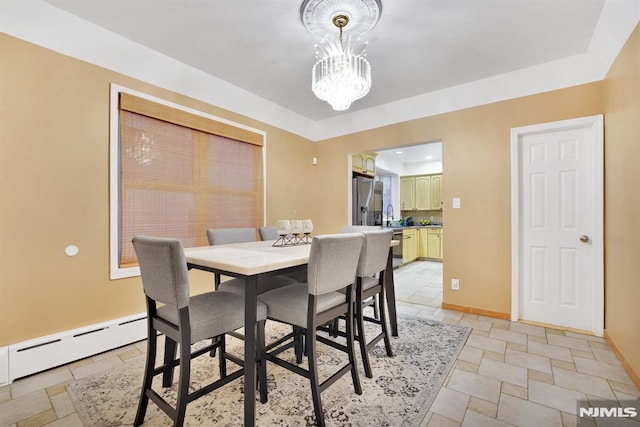 dining area with sink, a chandelier, and a baseboard heating unit