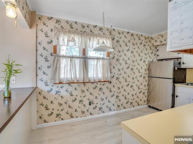 kitchen with stainless steel refrigerator, crown molding, white cabinets, and pendant lighting