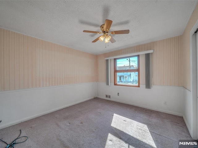 unfurnished room featuring a textured ceiling, light colored carpet, and ceiling fan