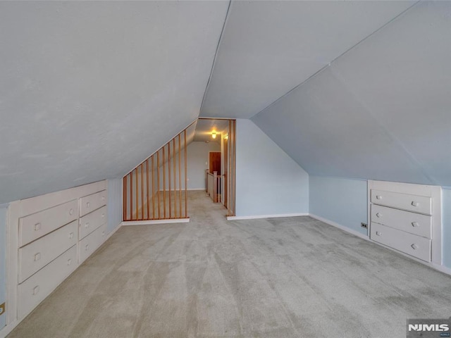 bonus room with light carpet and vaulted ceiling