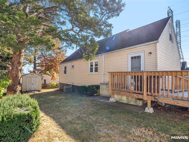 back of property with a storage unit, cooling unit, a yard, and a wooden deck